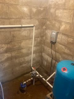 A blue water tank is sitting in a room next to a brick wall.