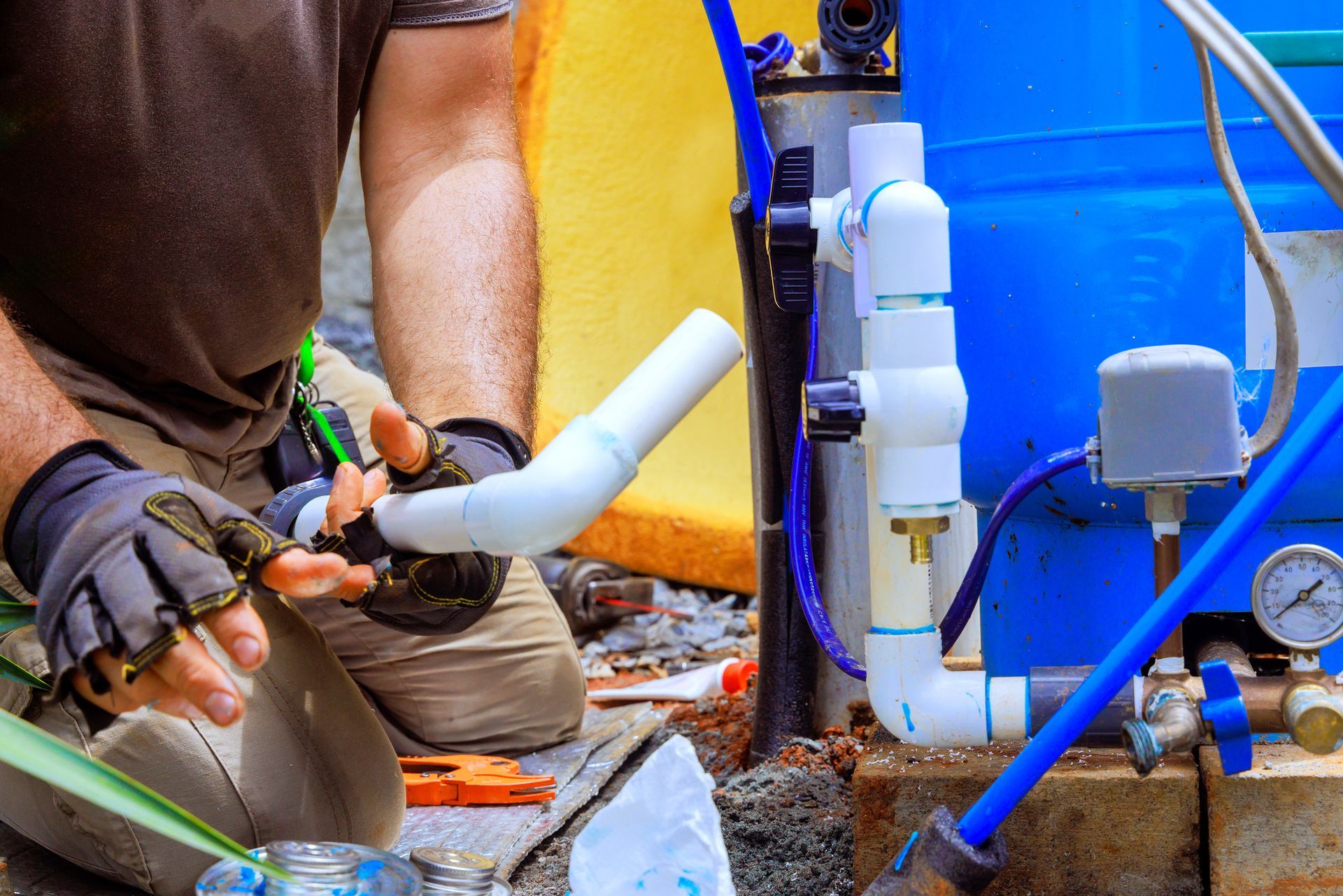 Worker performing professional water well repair using pipes and plumbing tools.