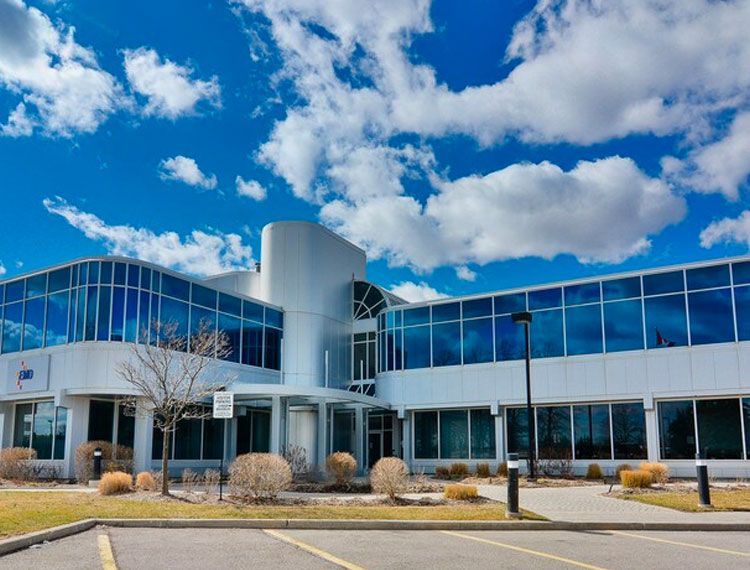 Modern, two-story building with blue-tinted windows against a bright blue sky with fluffy white clouds.