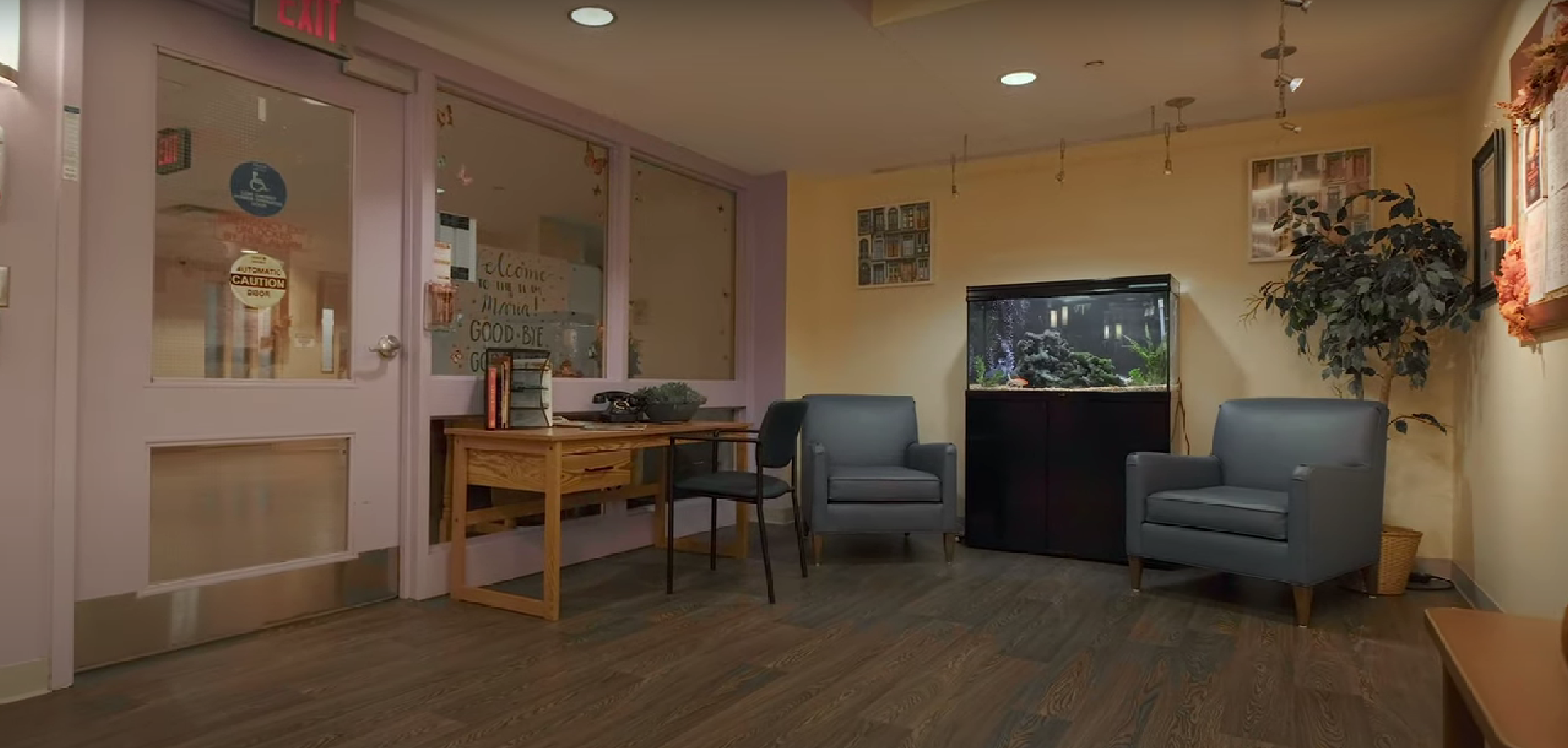 A waiting area with armchairs, fish tank, desk, and a potted plant.