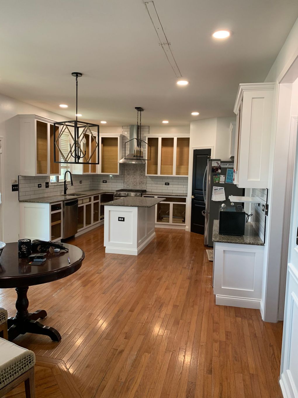 Open-concept kitchen and dining area with hardwood floors, granite counters, and white cabinets