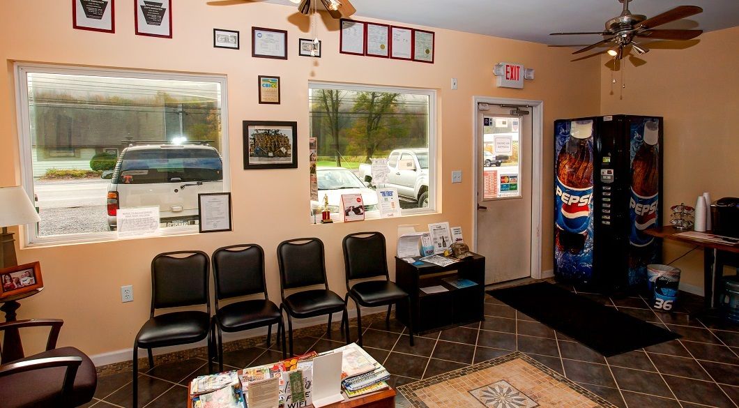 Waiting room with chairs, vending machines, and a window overlooking parked vehicles. | Absolute Auto Repairs & Sales