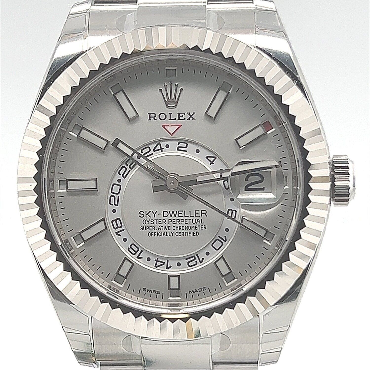 A silver rolex sky dweller watch is sitting on a white surface.