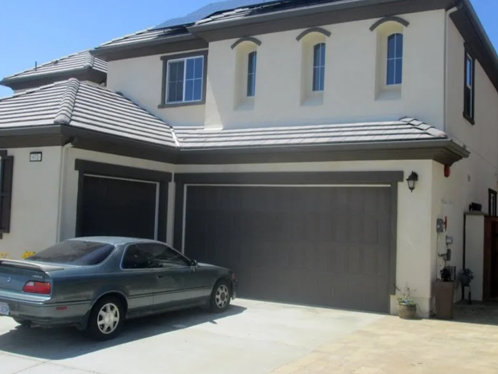 Two-story suburban house with a gray garage door and a car parked in the driveway