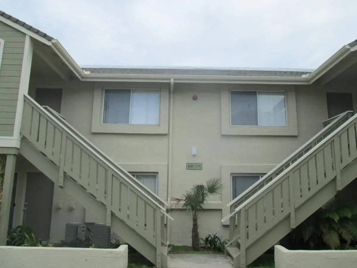 Apartment building courtyard with beige exterior and two stairways leading to upper units