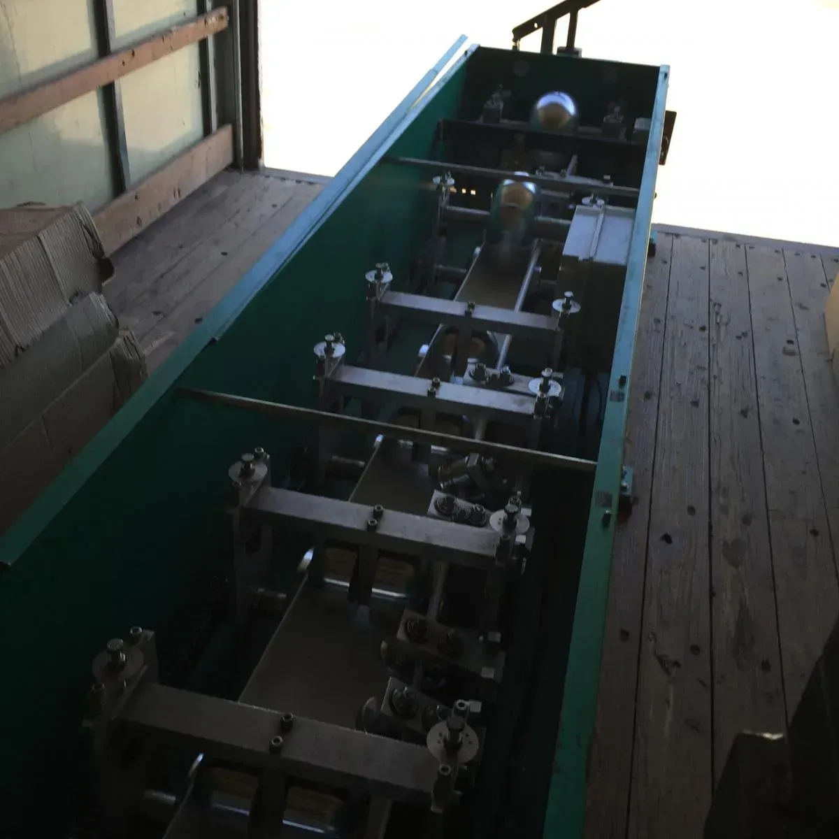 Long green industrial machine on a wooden deck, viewed from above.
