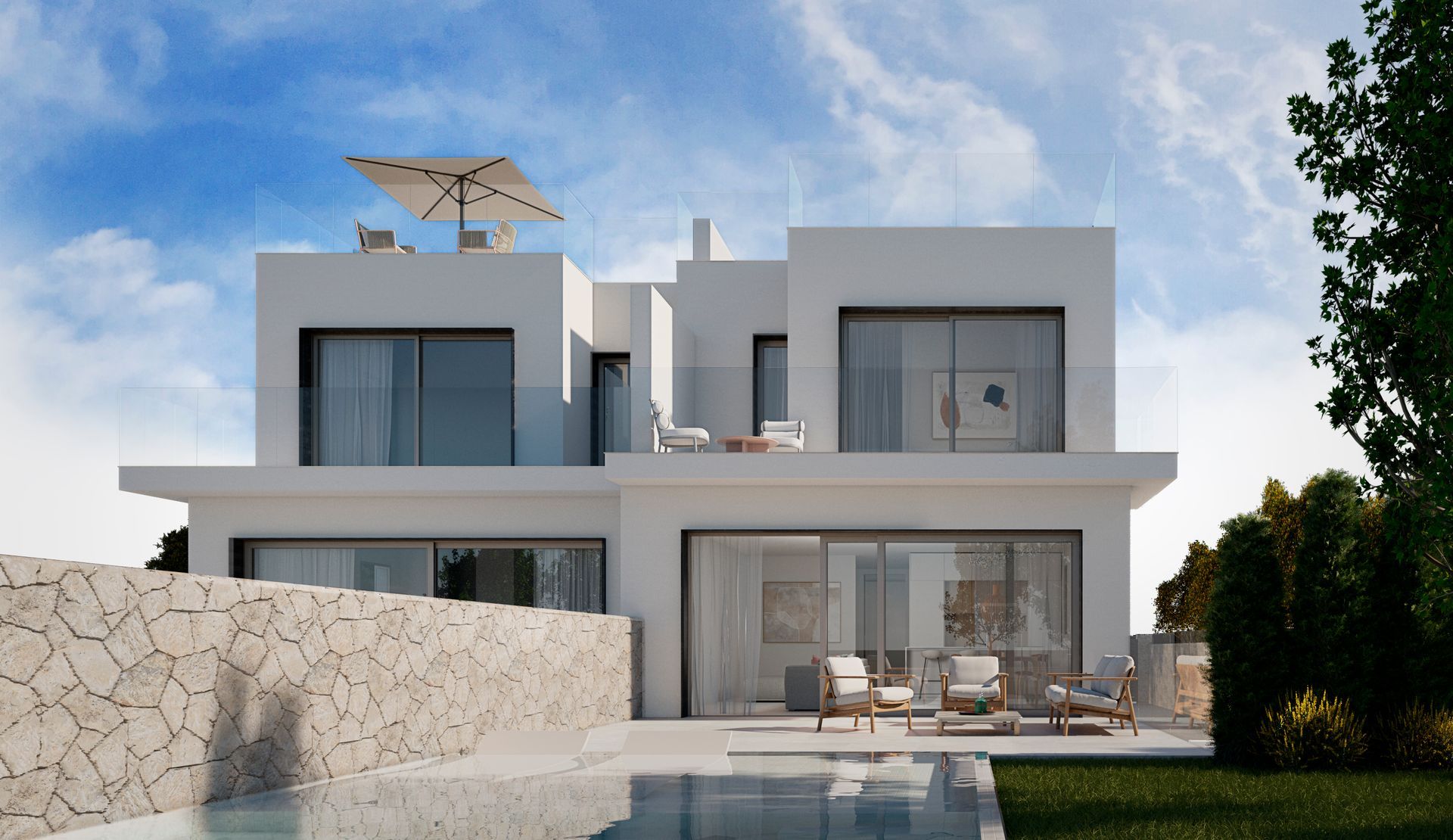 Moderna casa blanca de dos plantas con grandes ventanales, muro de piedra y muebles de patio bajo un cielo azul.