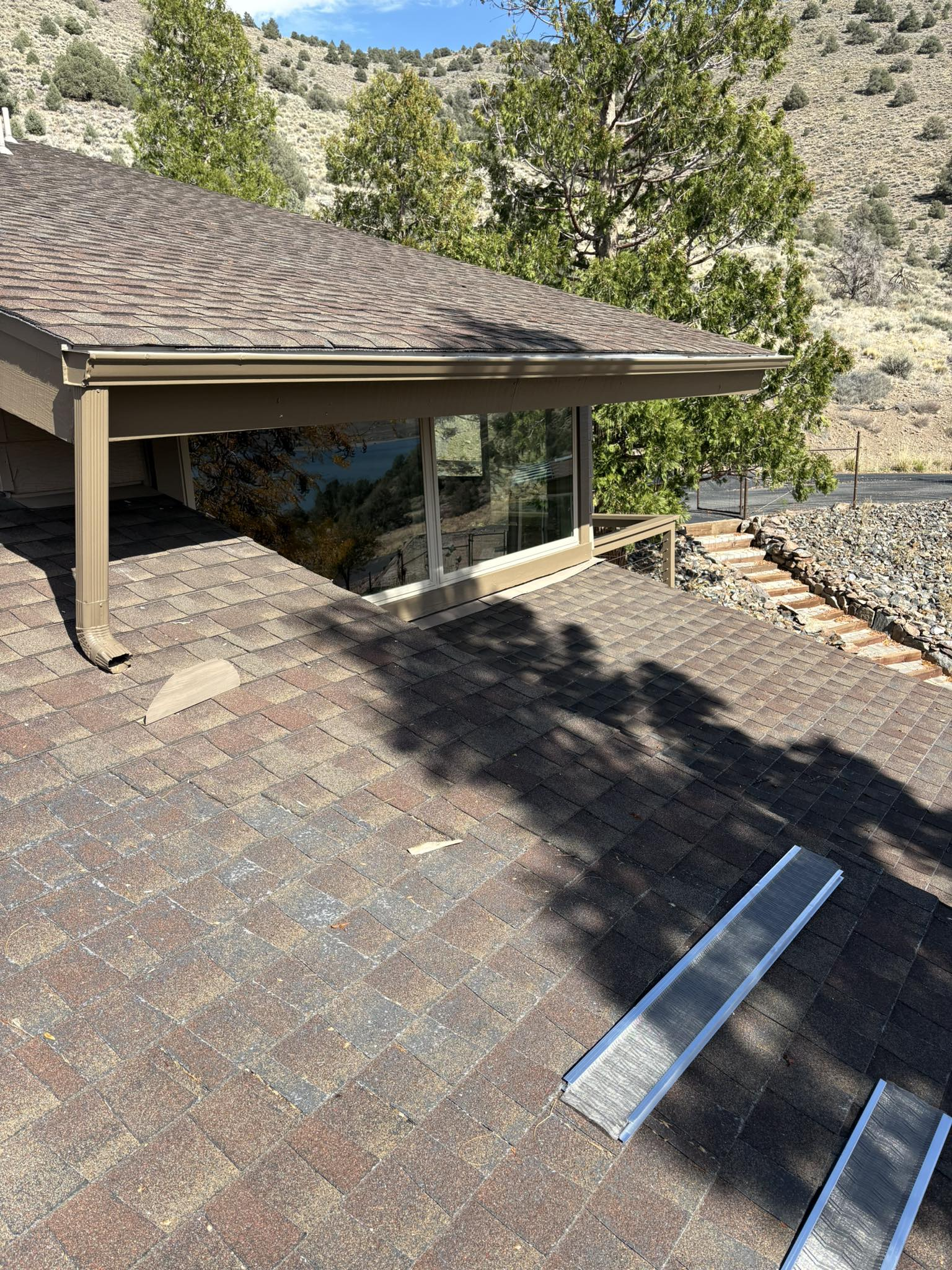 Overhead shot of a building with a brown roof and a window. Black ramp laying on the ground.