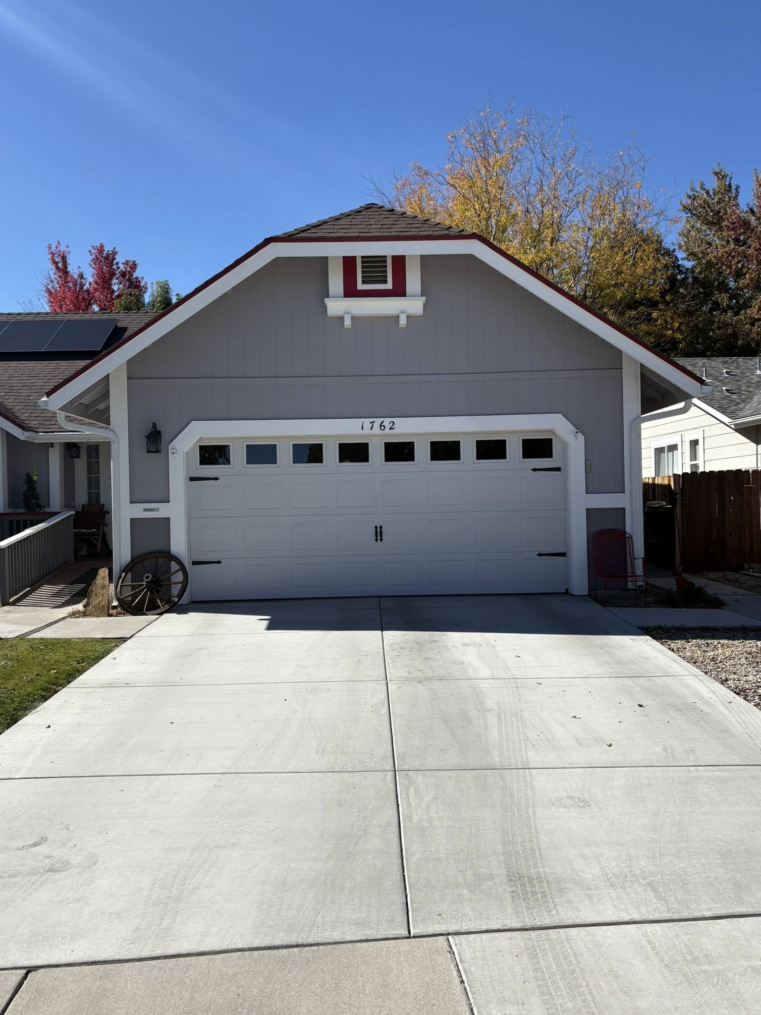 Gray house with a white garage door, concrete driveway, and a blue sky background.