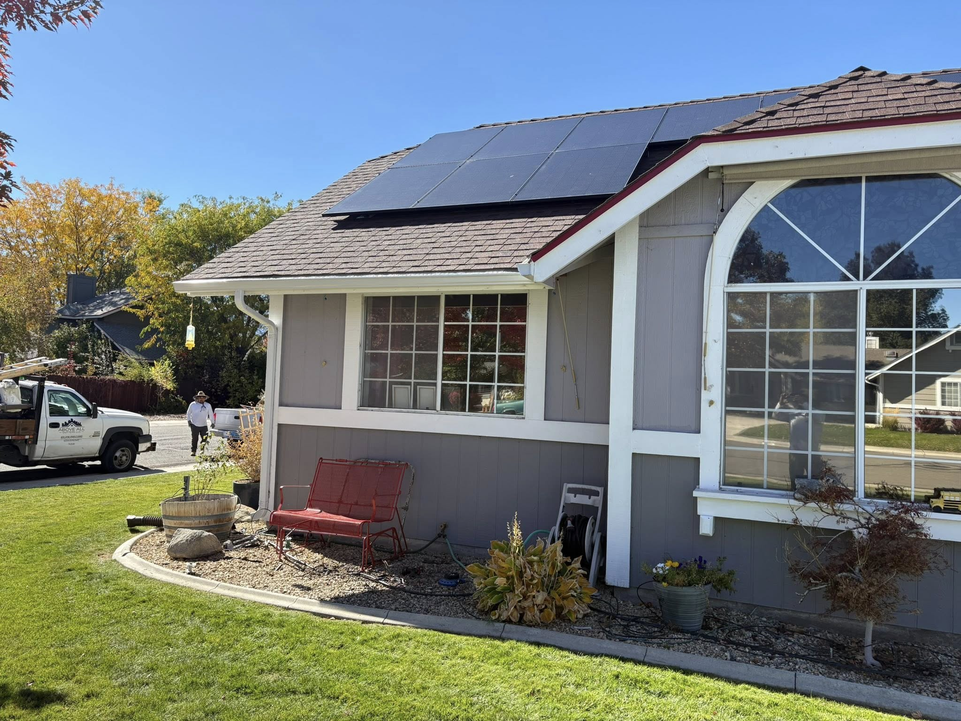 Solar panels on a house roof with a person walking in the background. Sunny day.