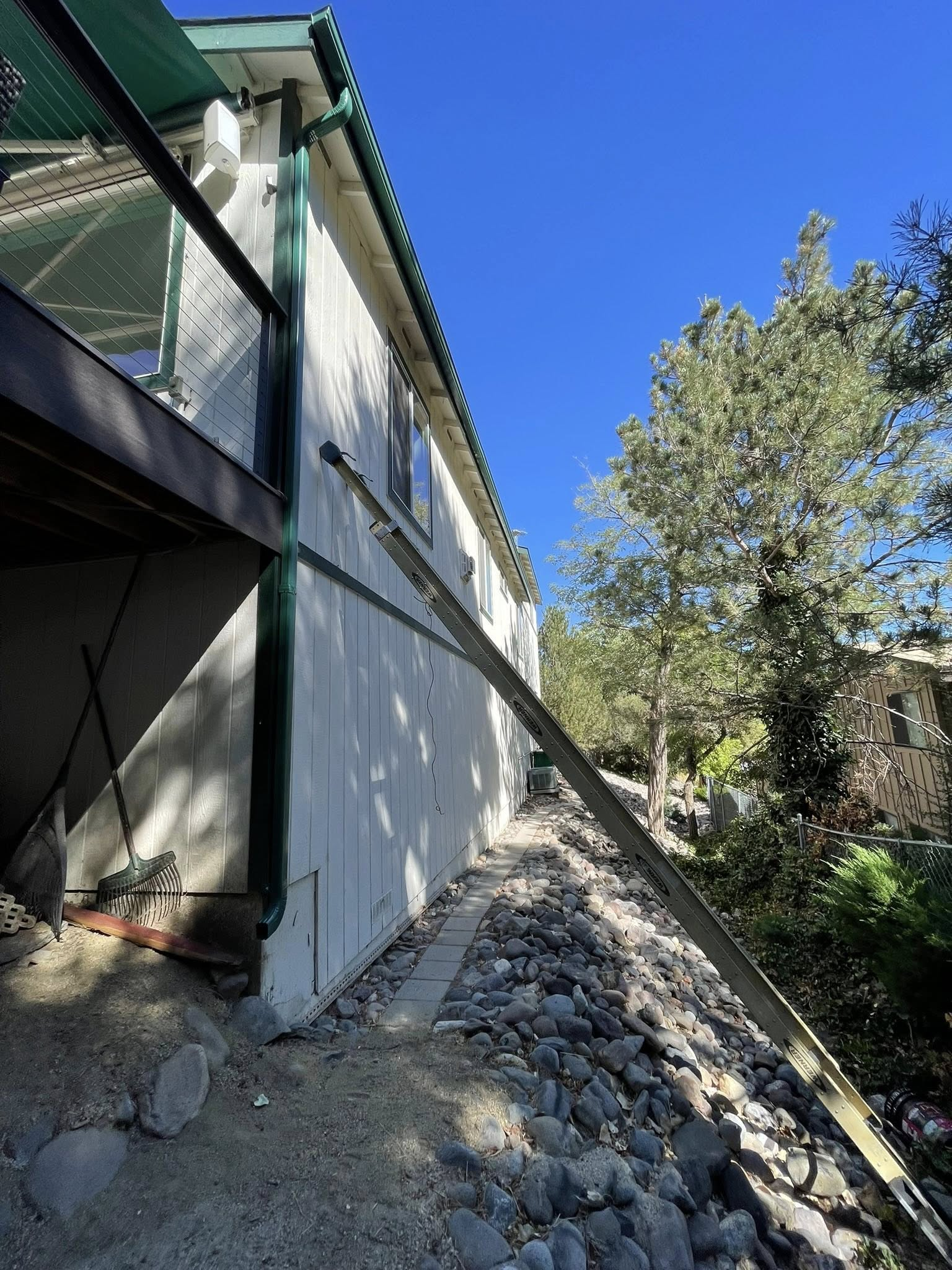Building exterior with a sloped rocky embankment; bright daylight.