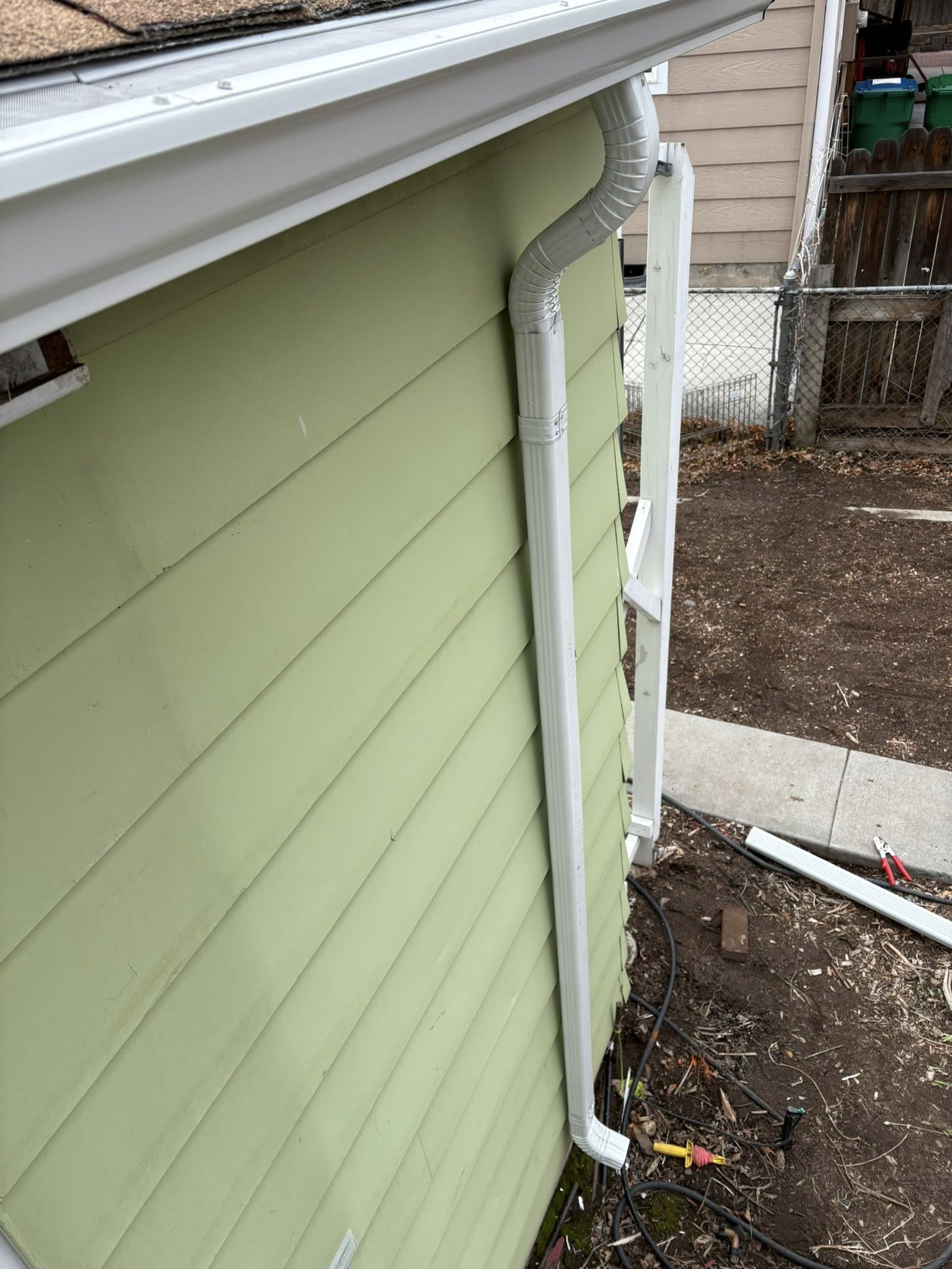White gutters and downspout on a light green house.