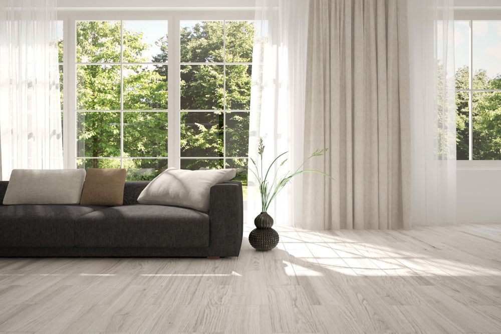A Living Room with A Black Couch and A Vase of Flowers in Front of A Large Window — Iconic Construction Industries in Cairns, QLD
