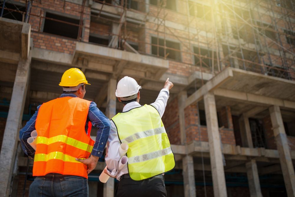Two Construction Workers Are Standing in Front of A Building Under Construction — Iconic Construction Industries in Cairns, QLD