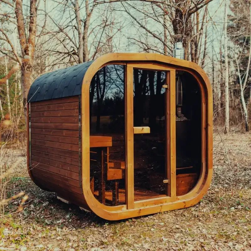 A black sauna is sitting in the middle of a lush green yard.