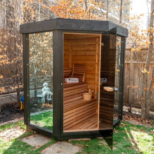 A wooden sauna in a backyard with a glass door.