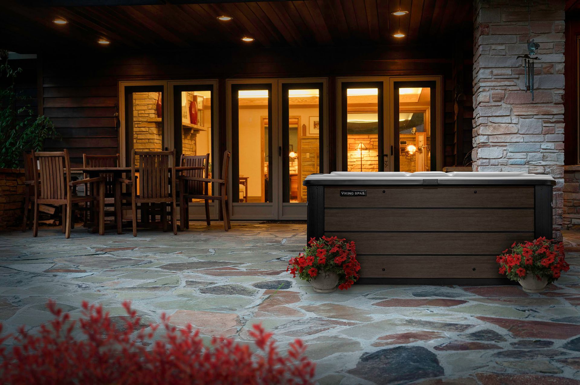 A hot tub is sitting on a stone patio in front of a house.