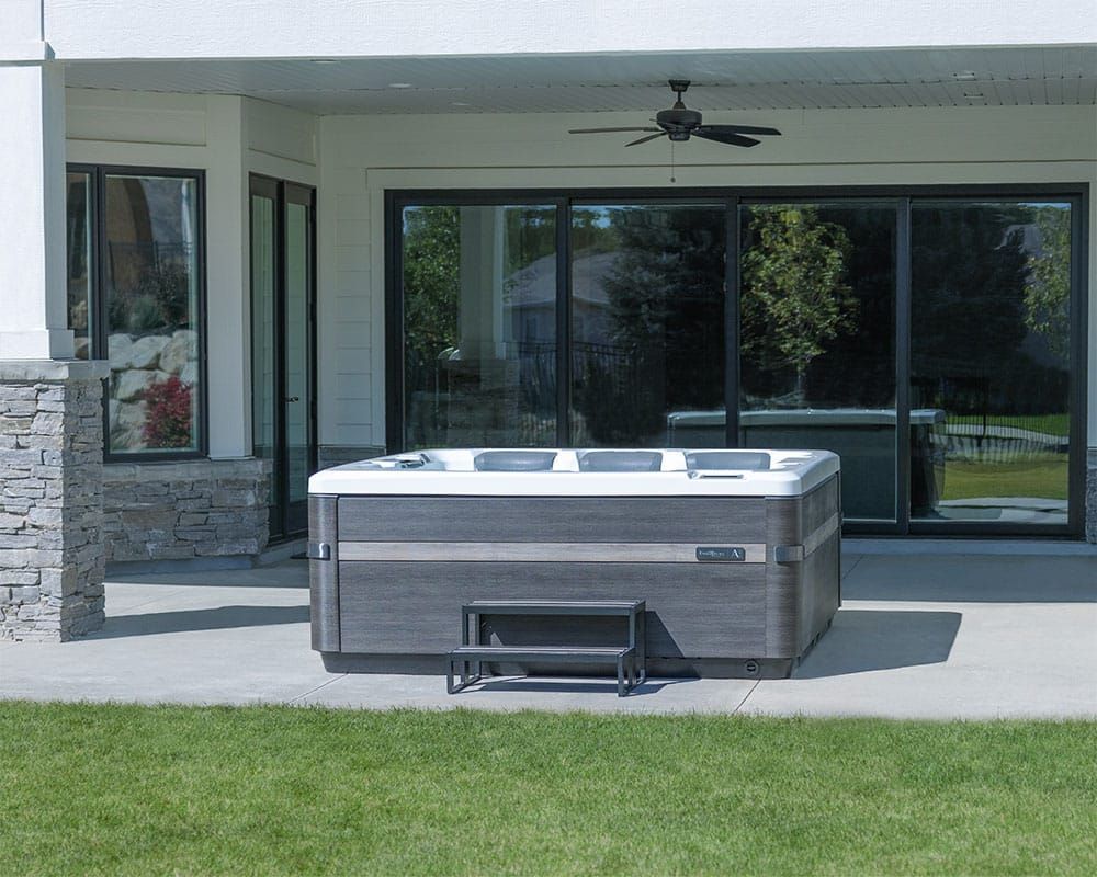 A hot tub is sitting on a patio in front of a house.
