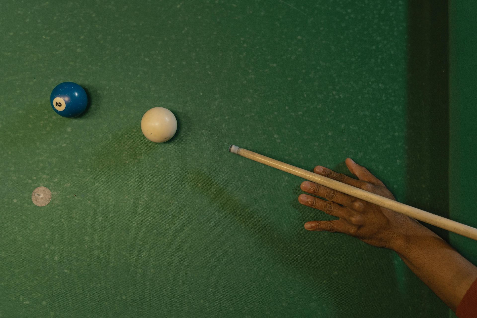 A person is holding a pool cue on a pool table.