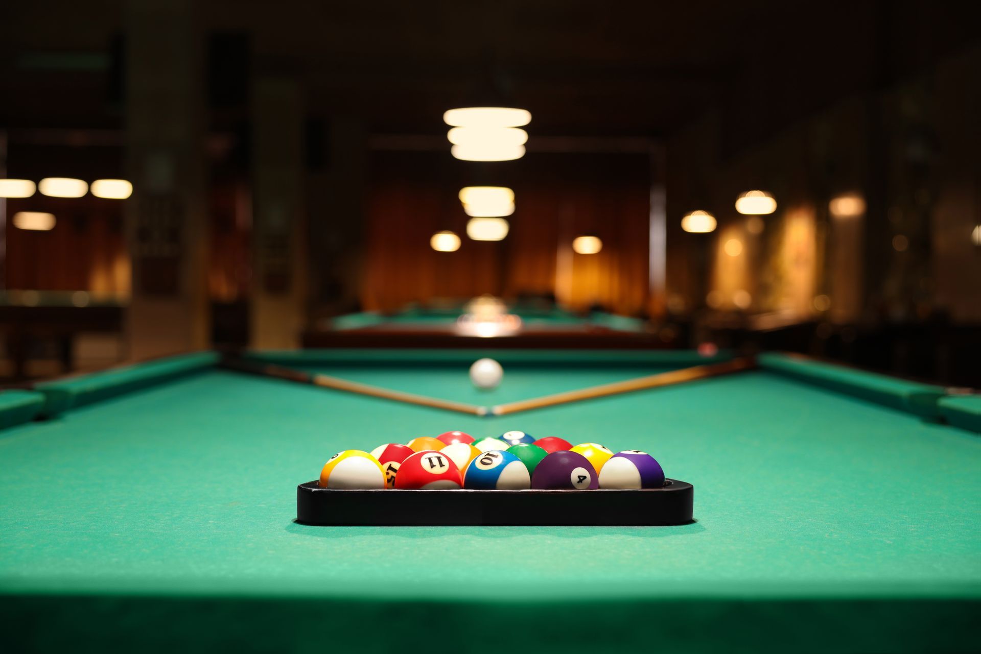 A pool table with balls and cues on it in a pool hall.