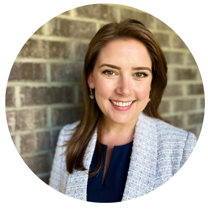 Kristin Hanna, CEO, smiling, wearing a blue top and gray blazer, in front of a brick wall.