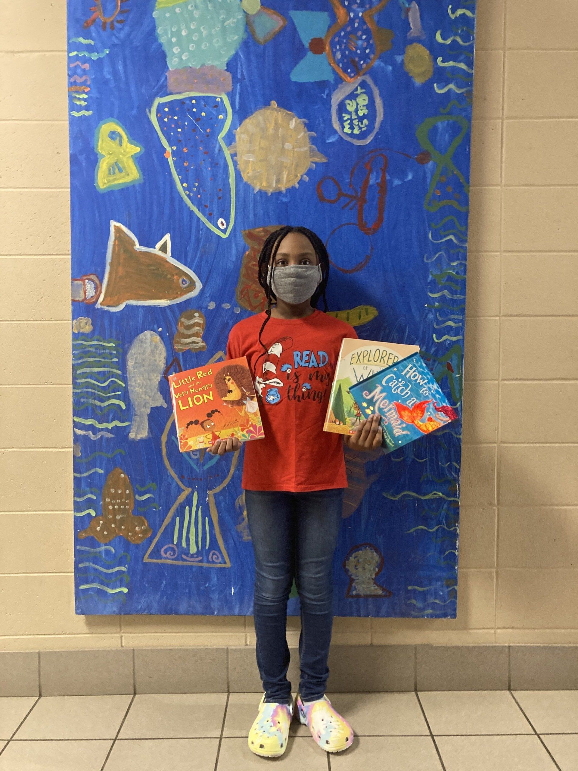 Child standing next to under-the-sea themed artwork at Boys & Girls Club