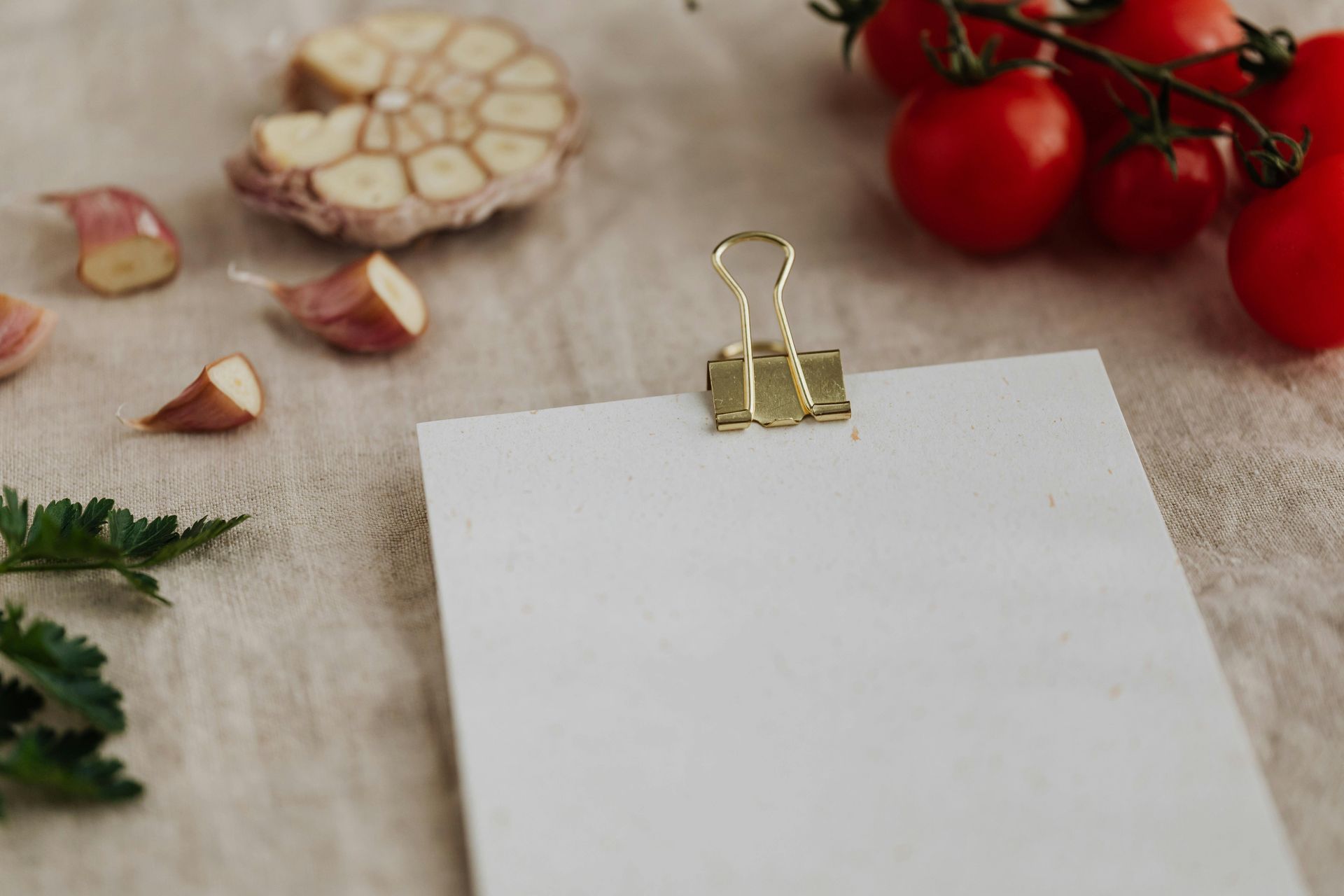 A piece of paper is sitting on a table next to tomatoes and garlic.