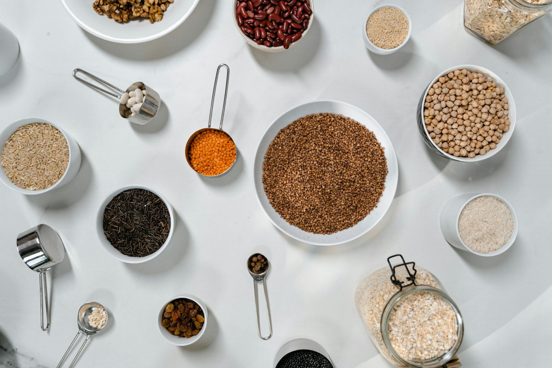 A table topped with bowls of grains and measuring cups.