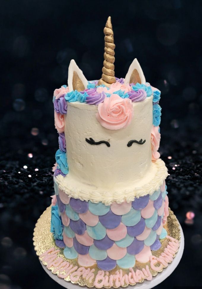 Unicorn cake with golden horn and ears, frosted in pastel colors, on a gold cake board, with