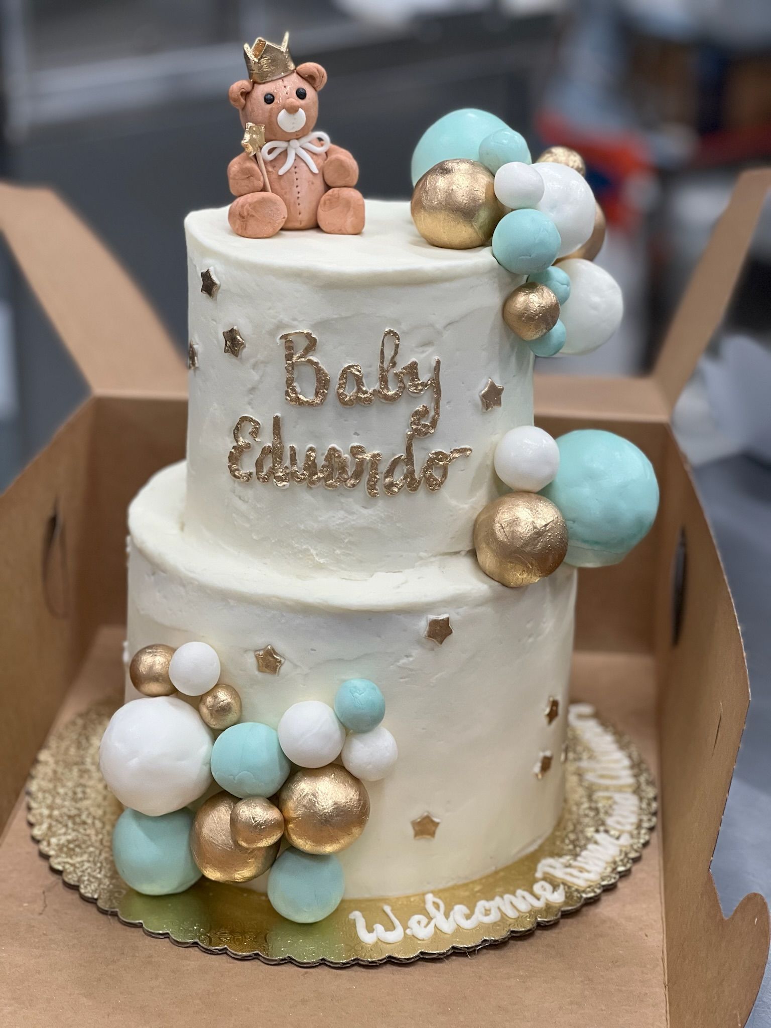 Two-tiered baby shower cake with teddy bear topper,