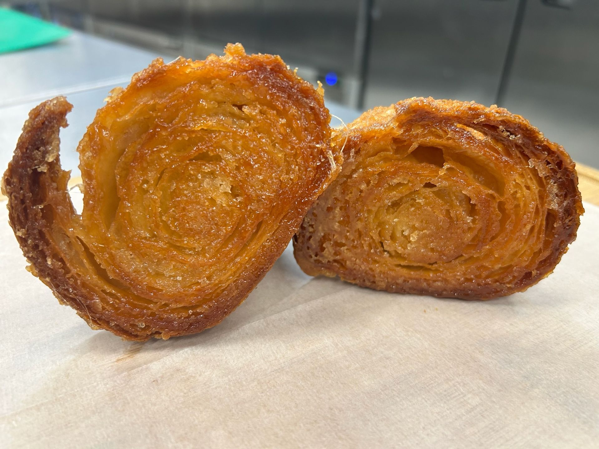 Two halves of a pastry, golden brown, layered, and sugared, on a white surface.