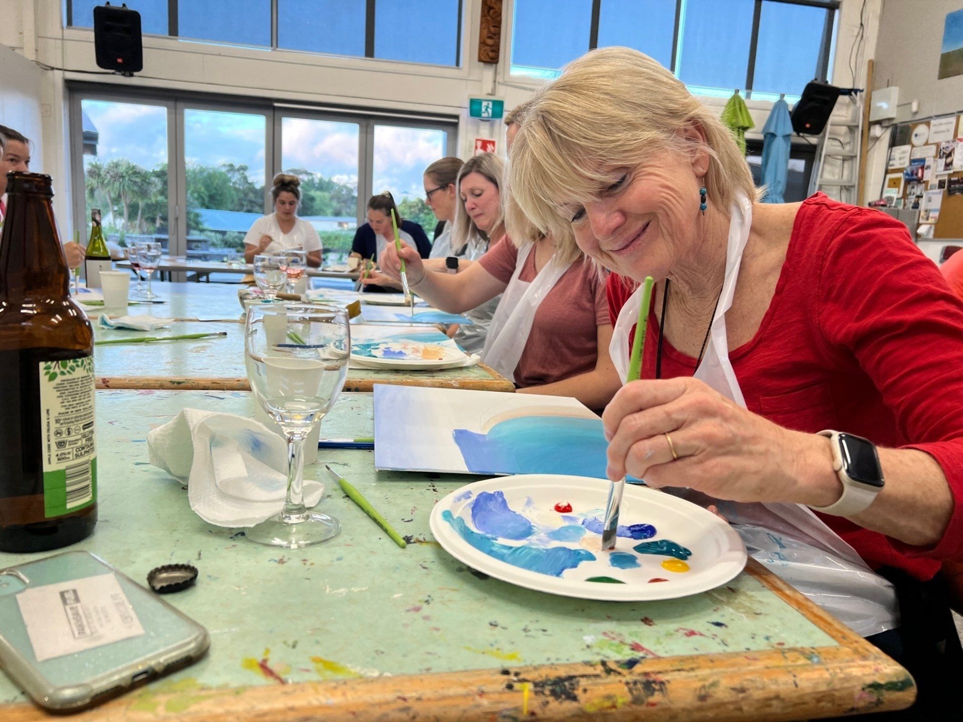 A woman is sitting at a table painting on a plate.