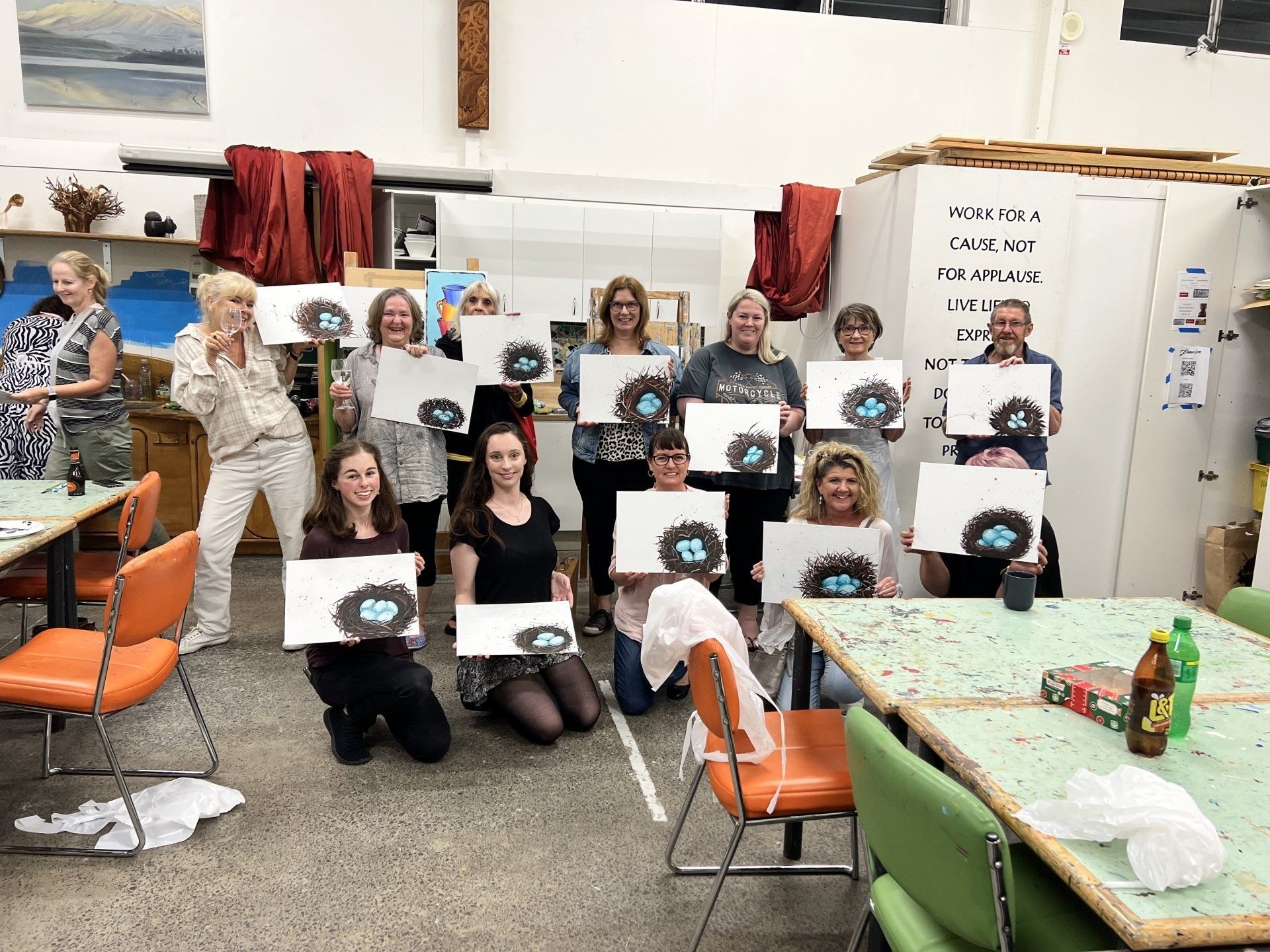 A group of people are posing for a picture in a room holding paintings.