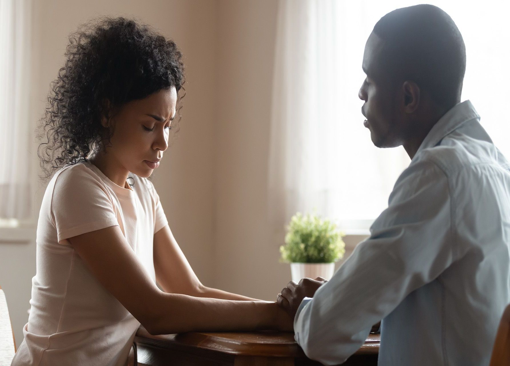 a man and a woman are sitting at a table holding hands .