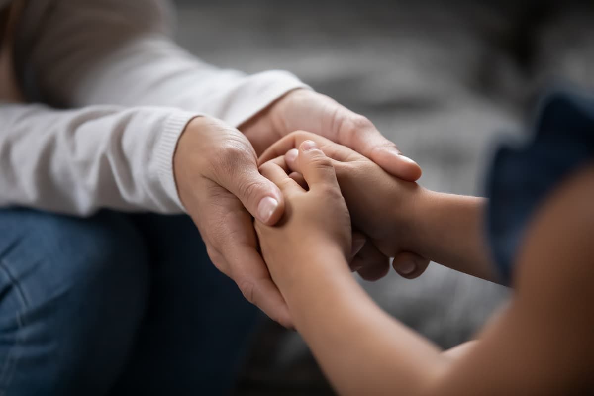 a woman is holding a child 's hand while sitting on a couch .