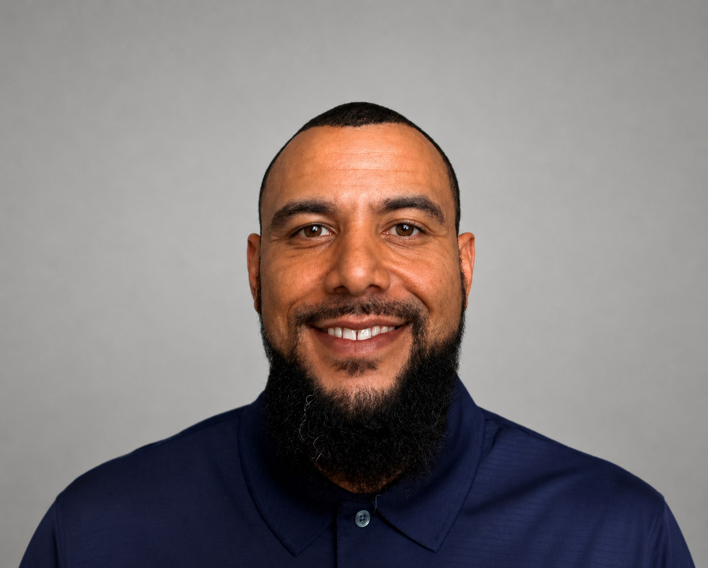Smiling man in a navy shirt against a plain gray background