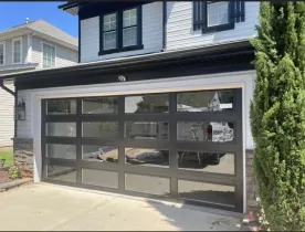 Modern two-story house with a black garage door and driveway in front