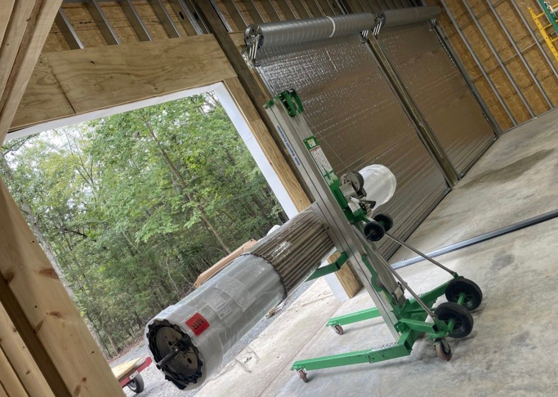 Construction site with green scaffold and wrapped materials inside a wooden-framed building.