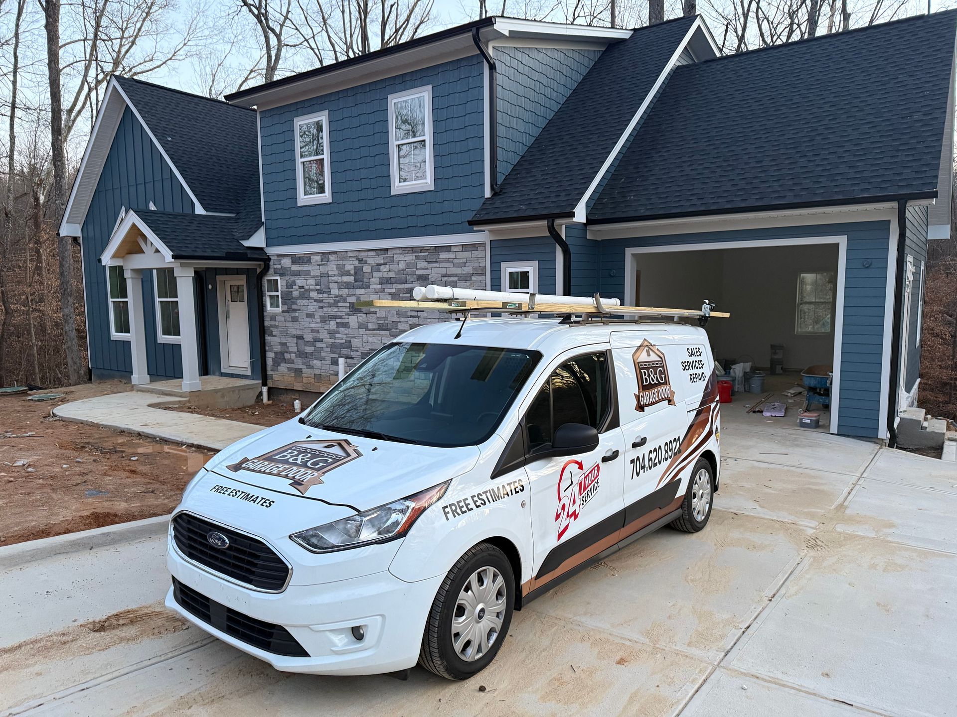 White service van parked in front of a gray house with an open garage door.