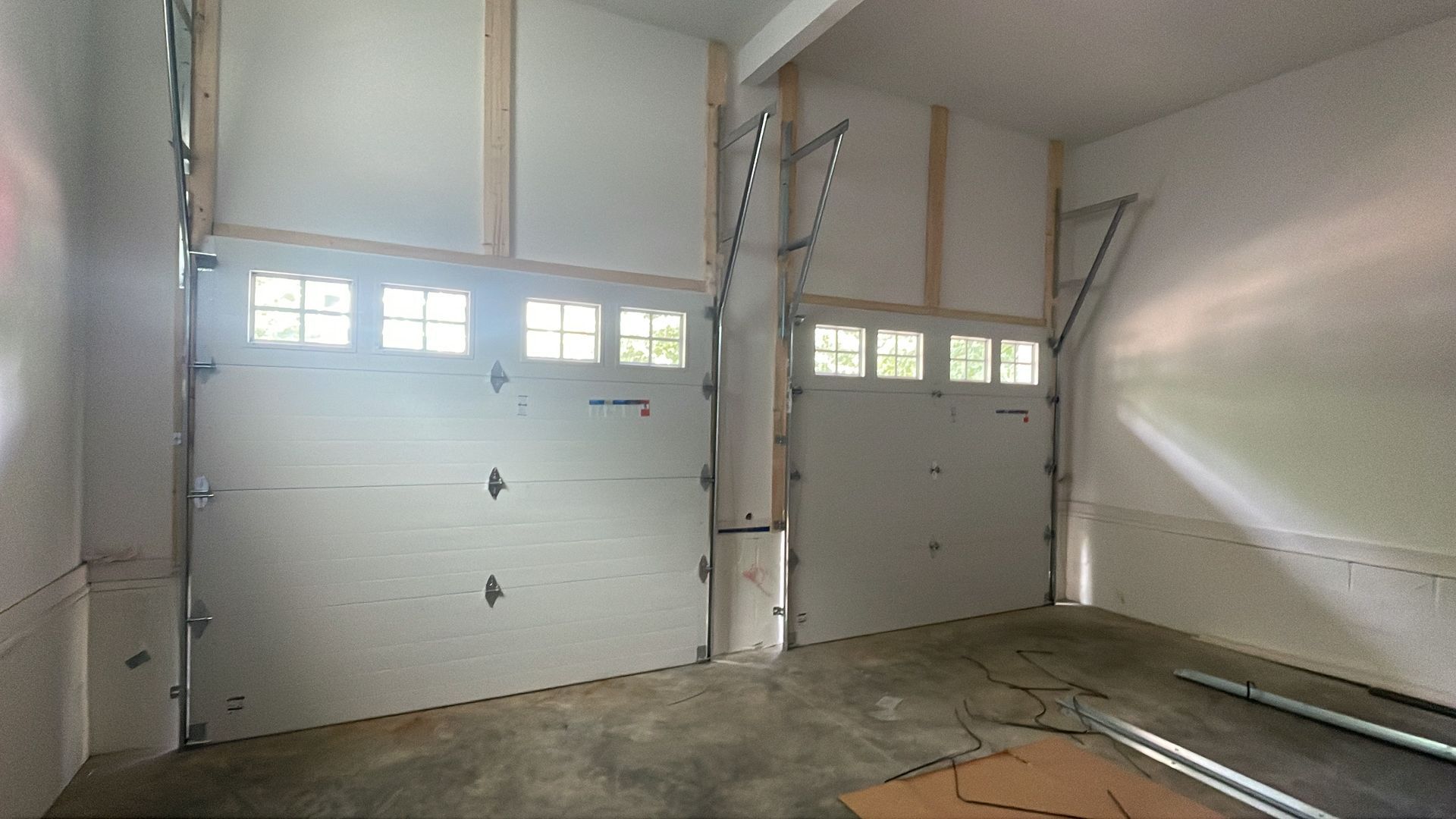 Empty two-car garage with white overhead doors and concrete floor