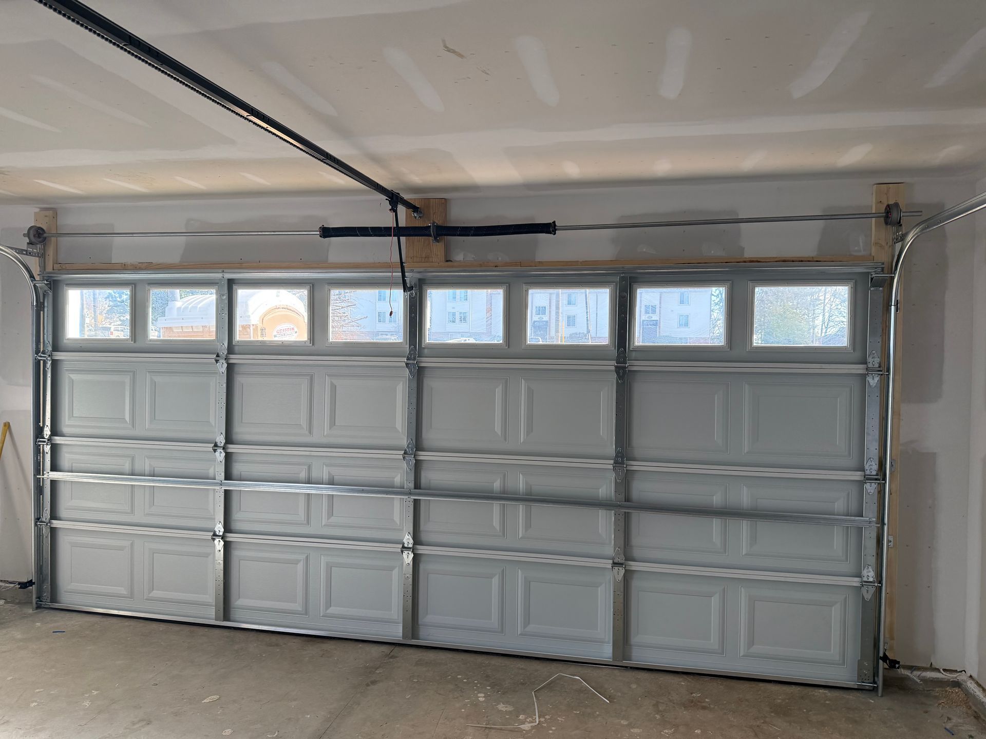 Closed white garage door with small windows in a garage interior