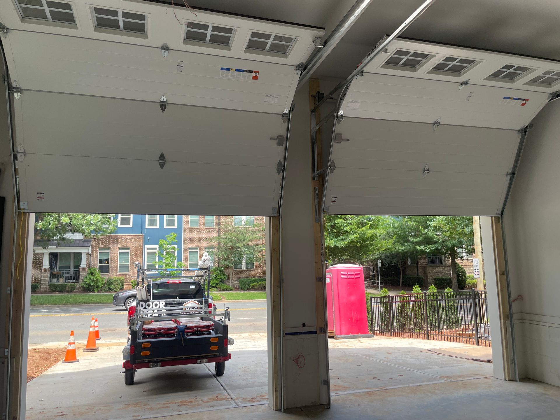 Open garage bays with a car parked at the entrance, street and traffic cones visible outside.