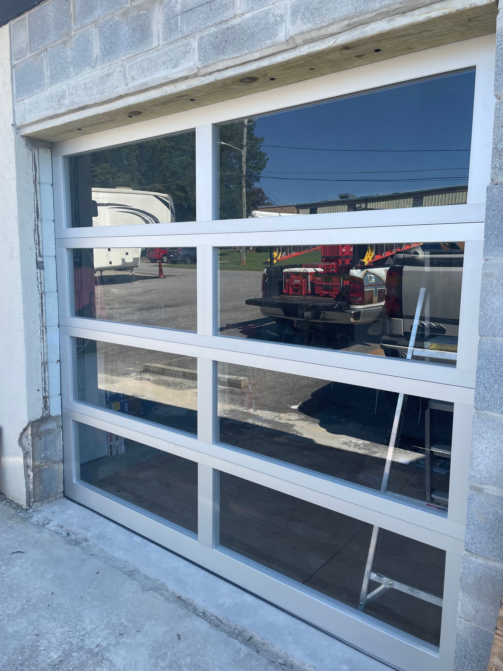 Garage door with white window panels reflecting a red tractor outside.