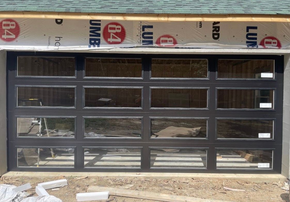 Gray garage door with small upper windows on an unfinished building exterior