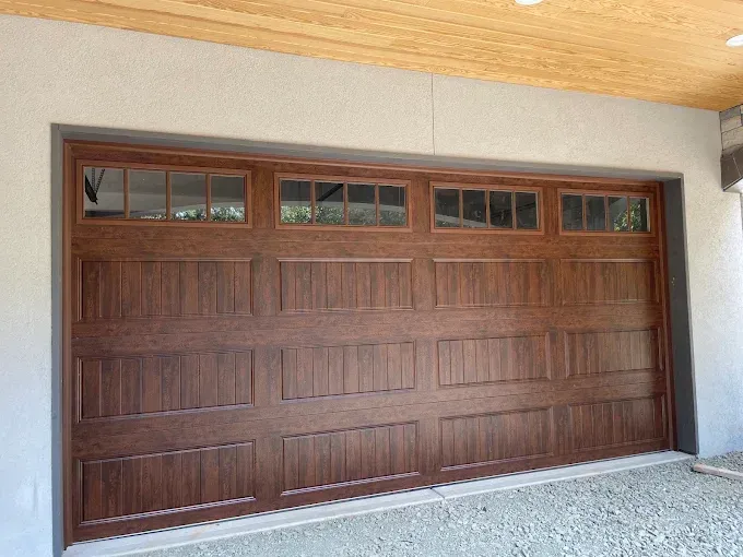 Wooden garage door with upper windows set in a beige stucco exterior.