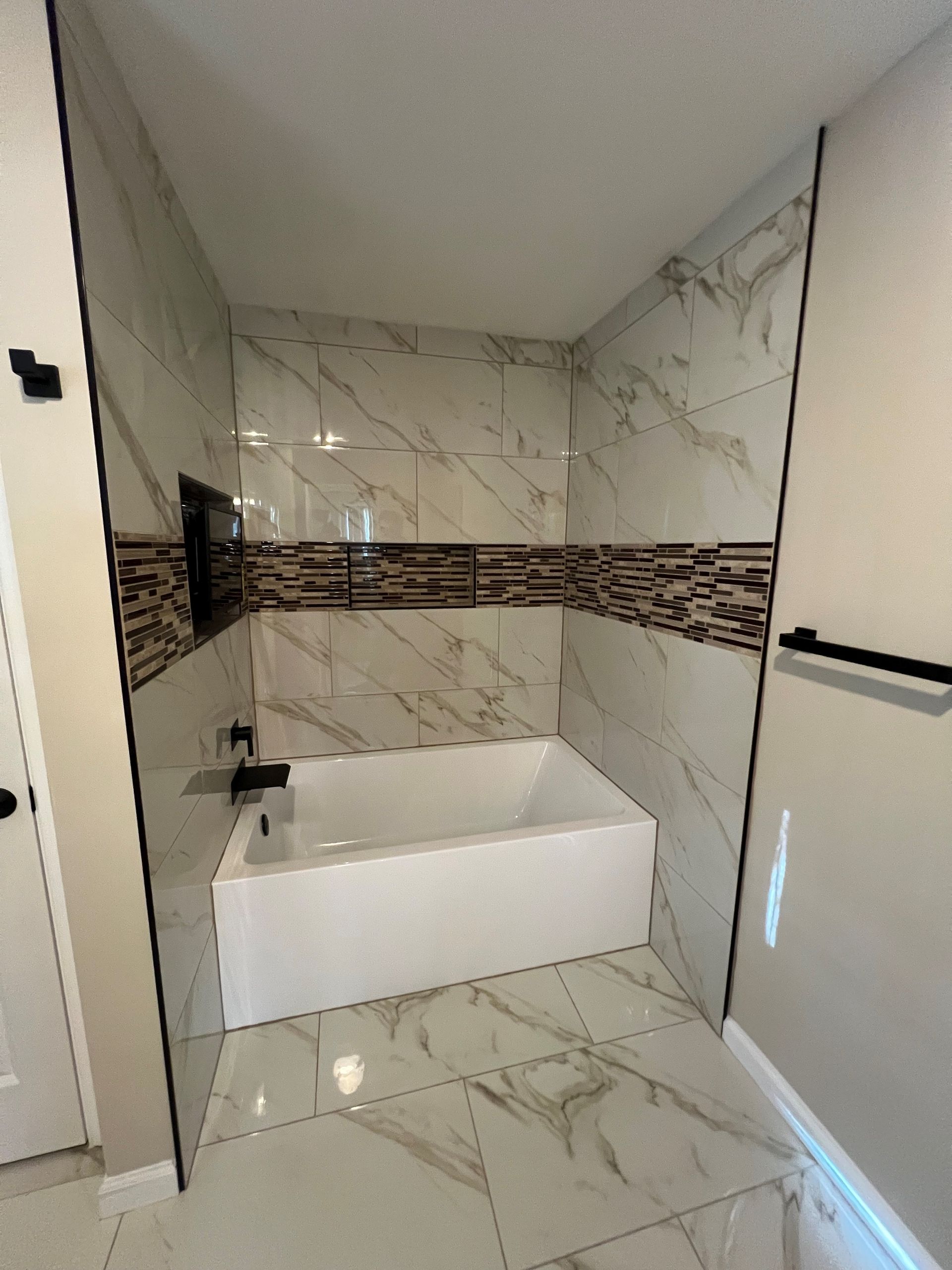 Modern bathroom with white marble tile, floating sink, and horizontal brown accent band
