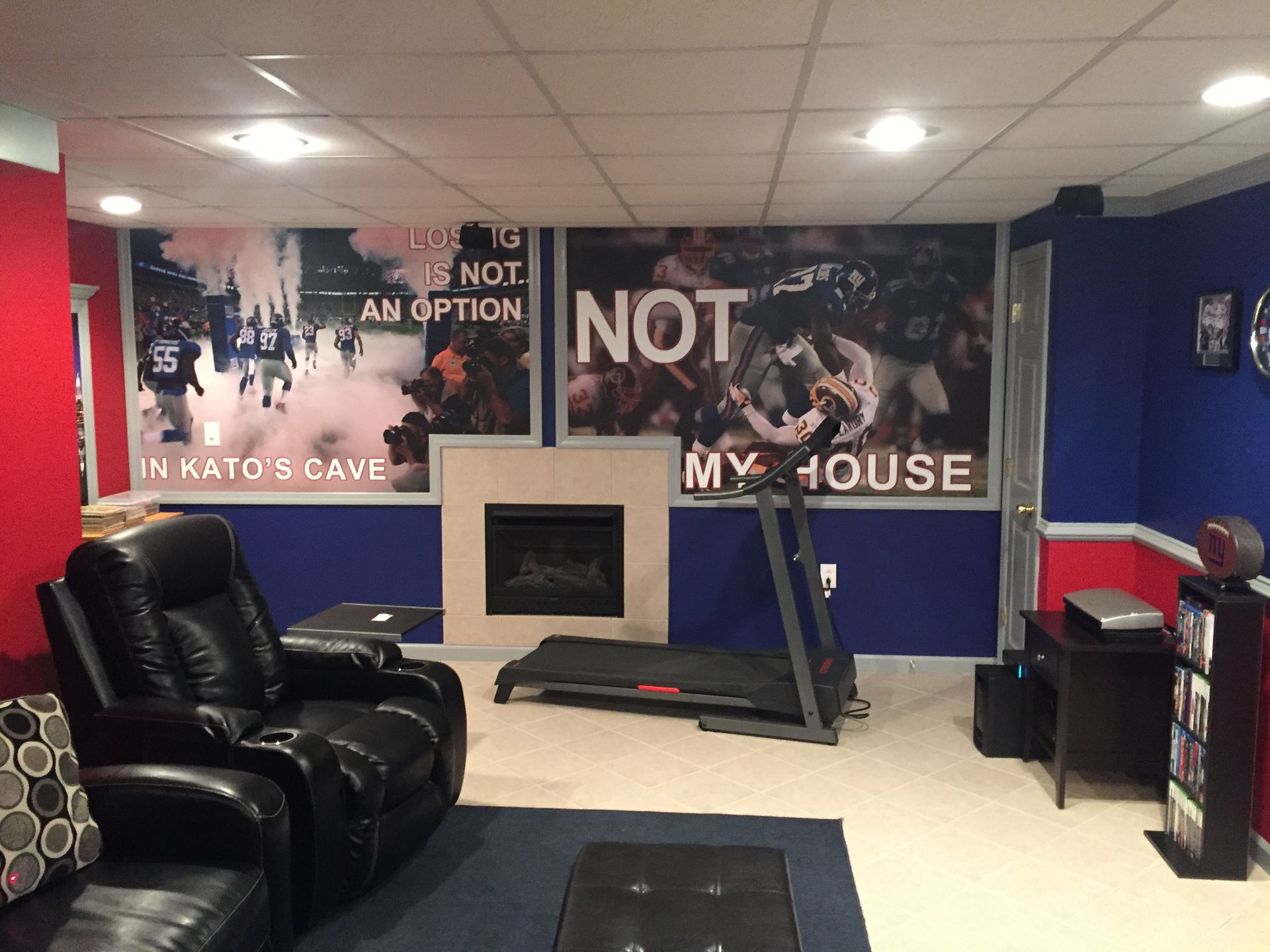 Basement lounge with black chairs, a fireplace, and wall mural reading “NOT MY HOUSE.”