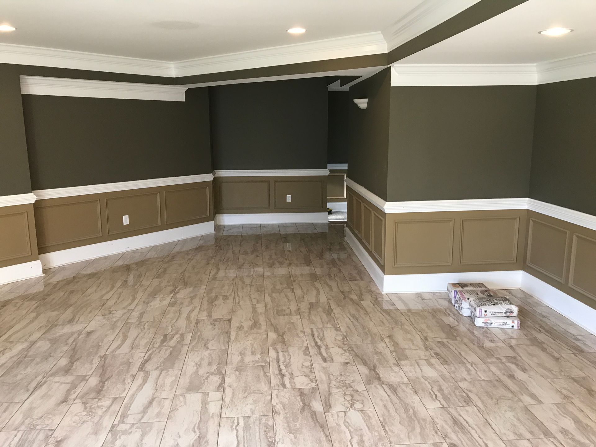 Empty room with dark walls, white trim, tan wainscoting, and wood-look flooring
