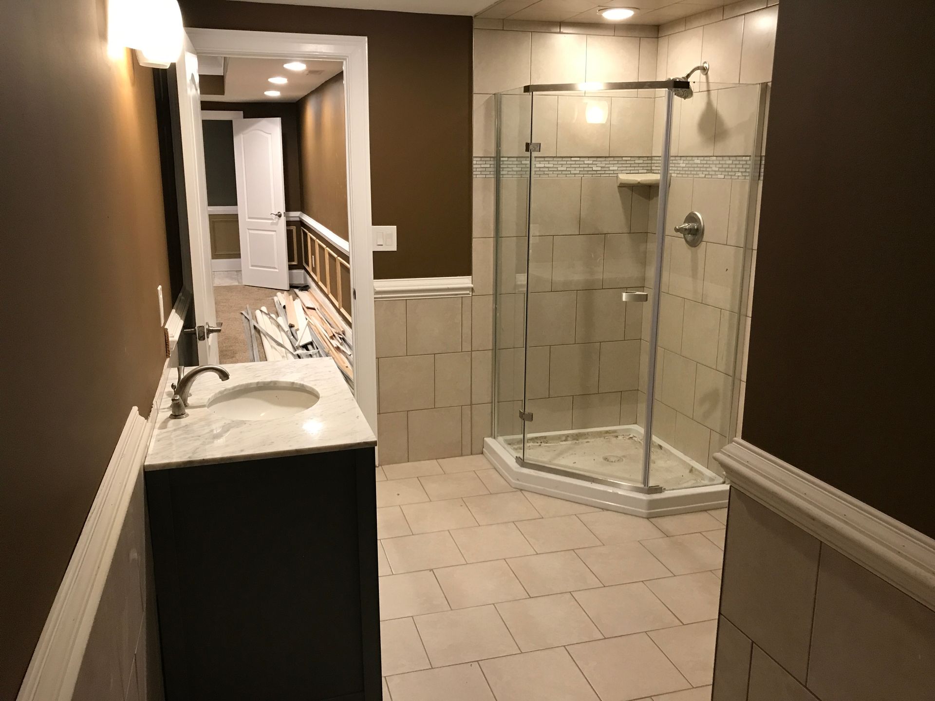 Spacious bathroom with double vanity, tiled floor, and glass-enclosed shower stall