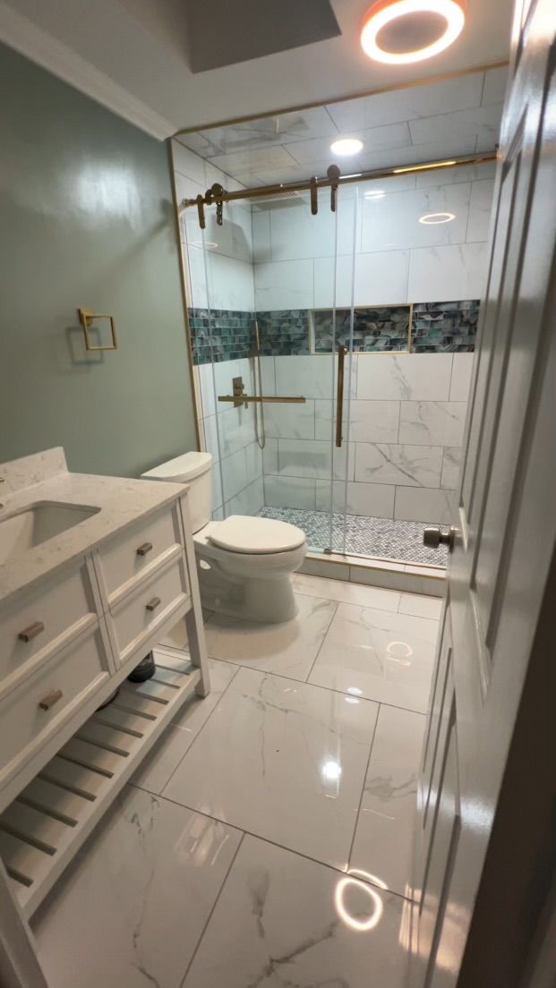 Modern bathroom with glass shower, white vanity, and glossy tile floor
